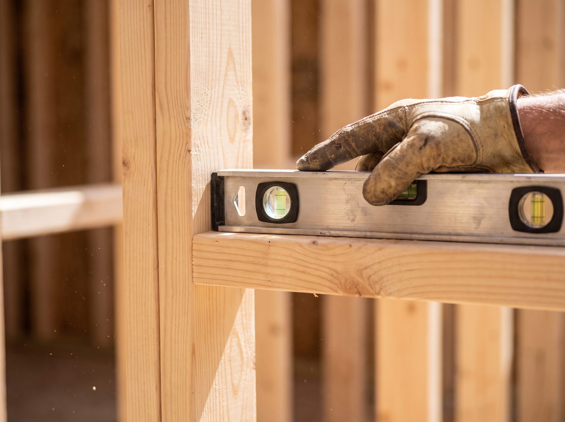 Contractor's hand checking a level against fresh wood framing